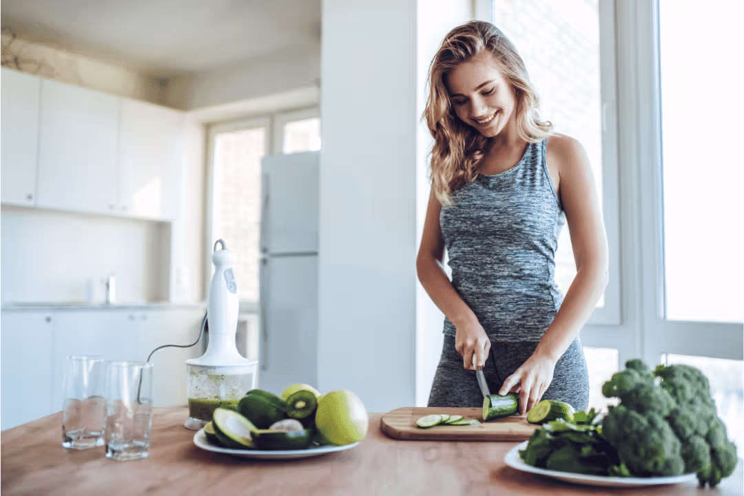 young woman in workout clothes chopping green vegetables