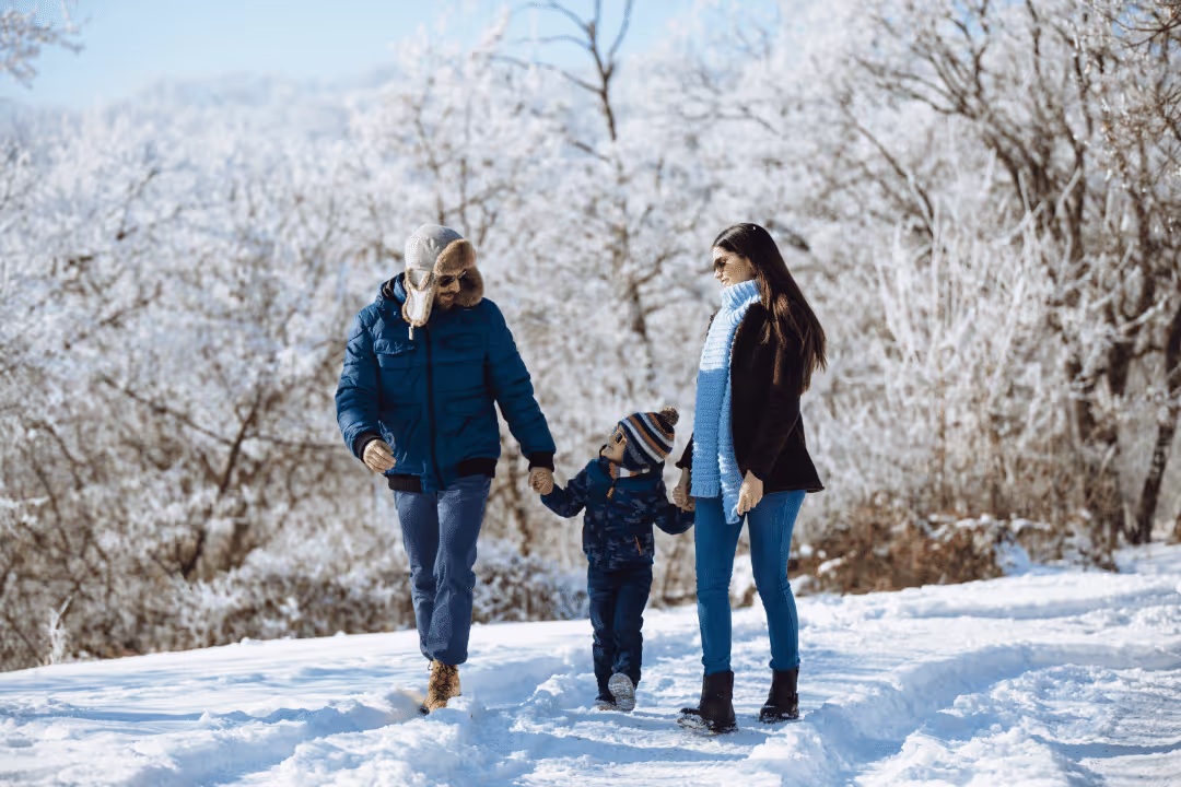 young couple with toddler walking through the snow