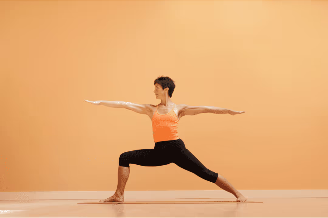 woman doing yoga in orange top in front of orange background