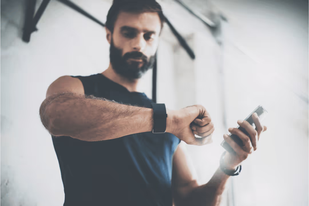 man checking watch fit bit pedometer during workout holding cell phone