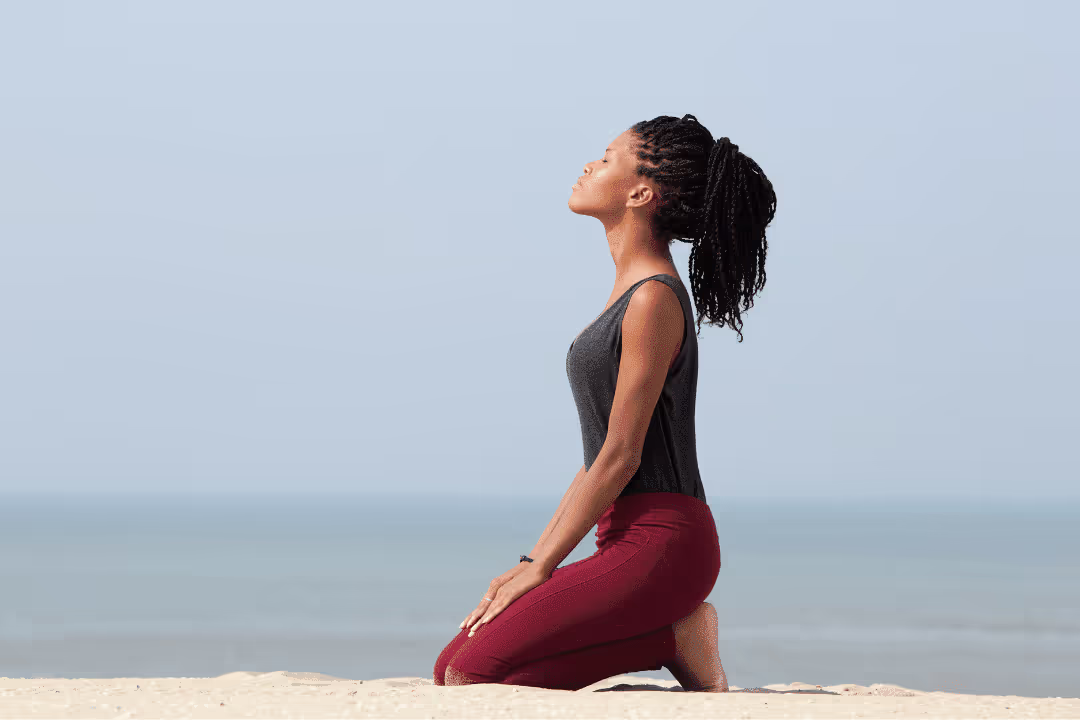 woman meditating on beach in workout clothes