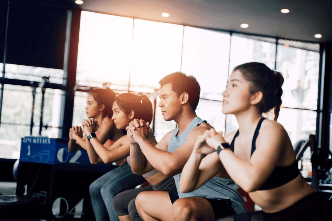 group of people in a gym taking a class squats sunshine