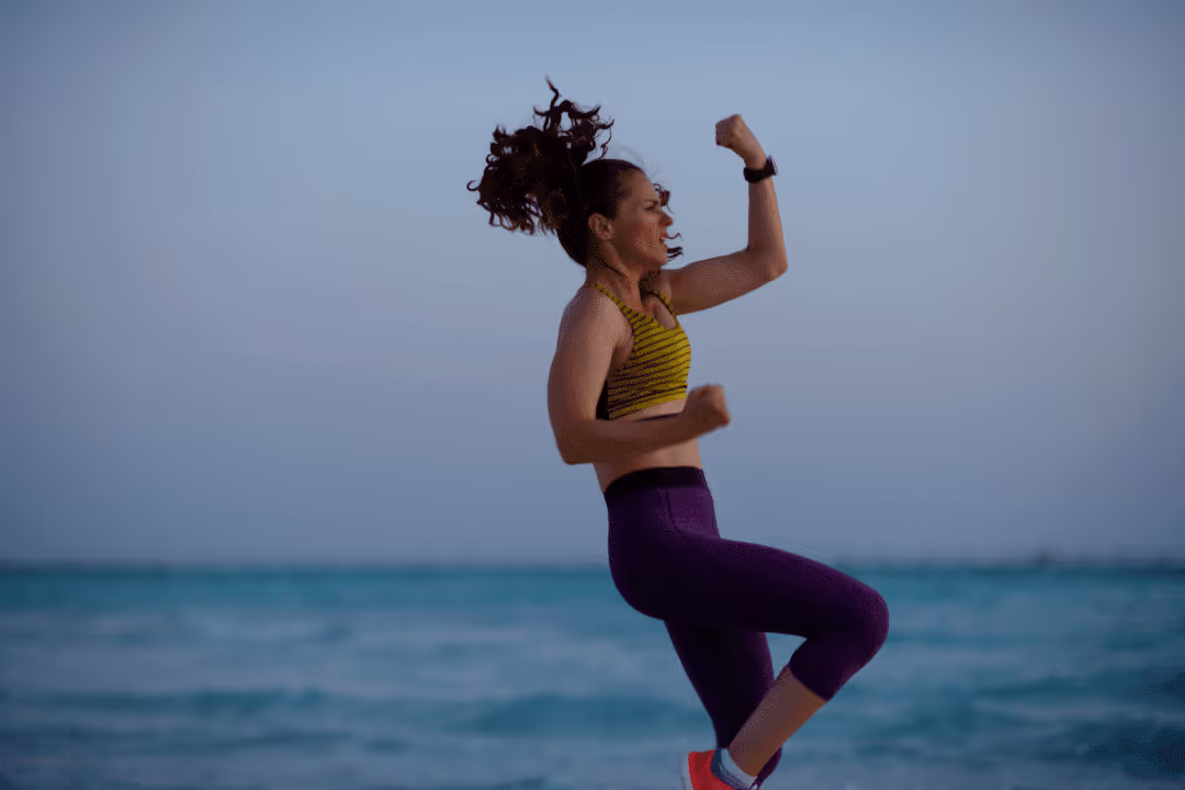 woman jumping doing strenuous workout on the beach athletic clothing