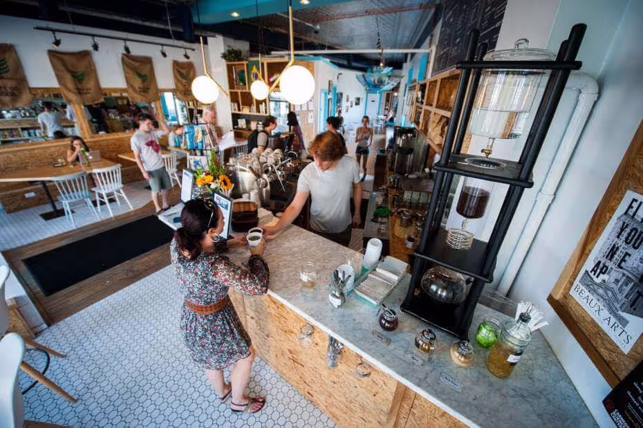 woman ordering coffee male barista cute coffee shop marble counter coffee maker white tile lights trendy