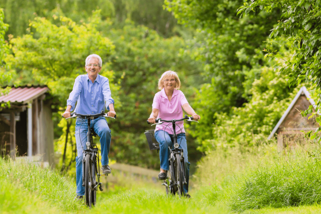 couple riding bikes through a field forest smiling wooden sheds summer green
