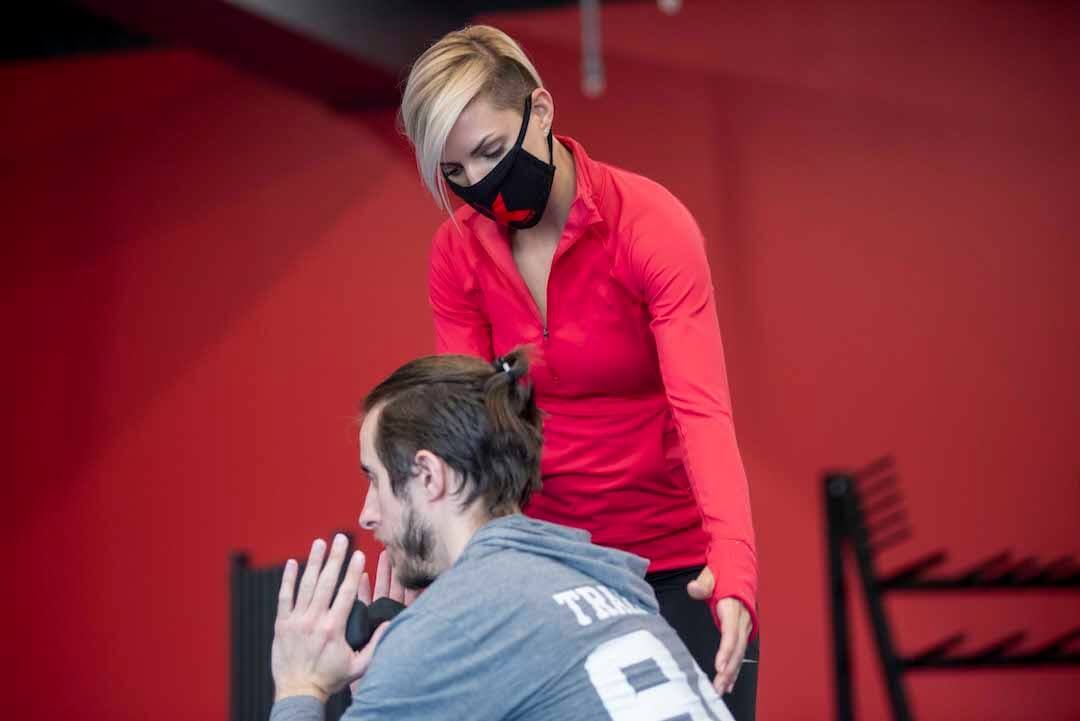 personal training session red background weights crunches red quarter zip man and woman assistance