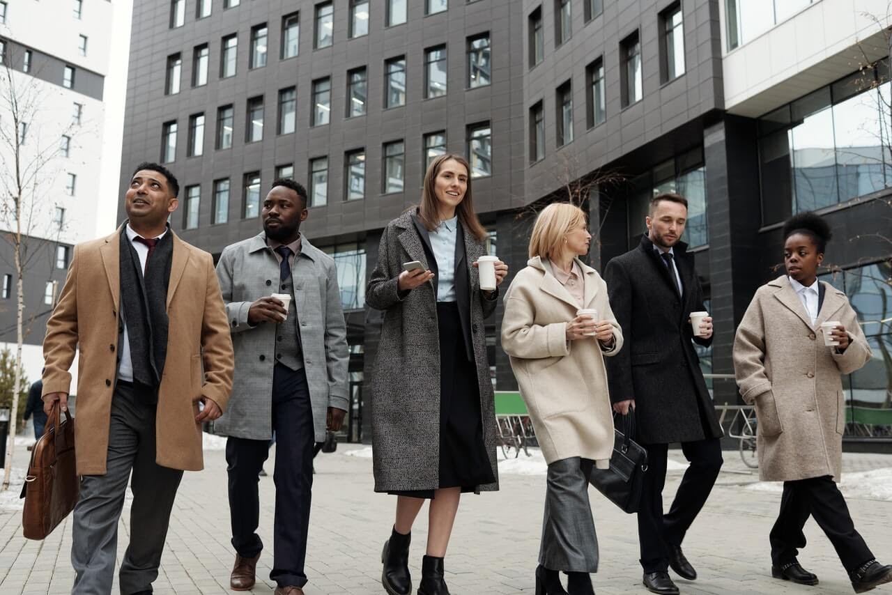 group of people coworkers waking coffee morning city gray building winter coats
