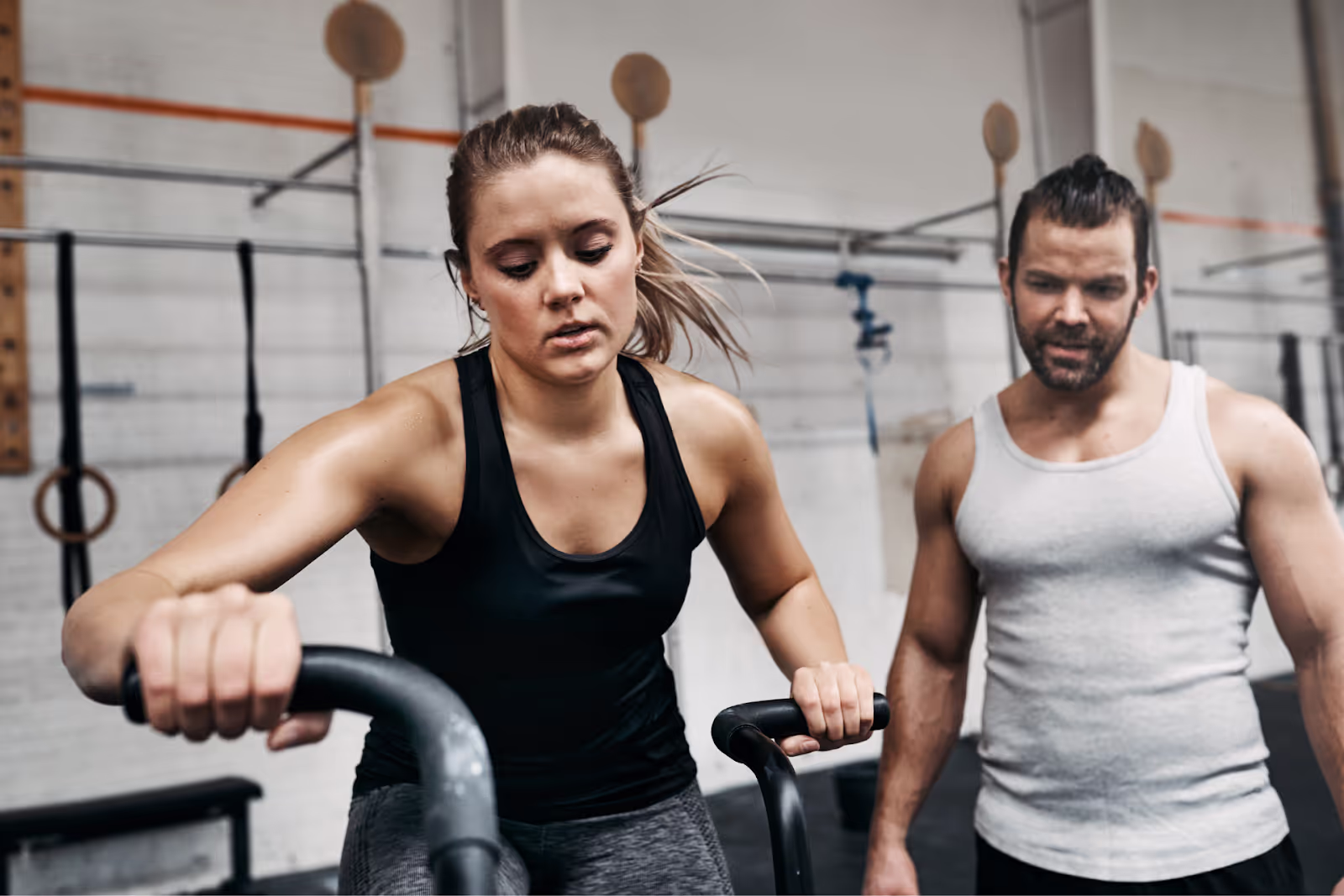 Fit Young Man Watching His Gym Partner Ride a Bike