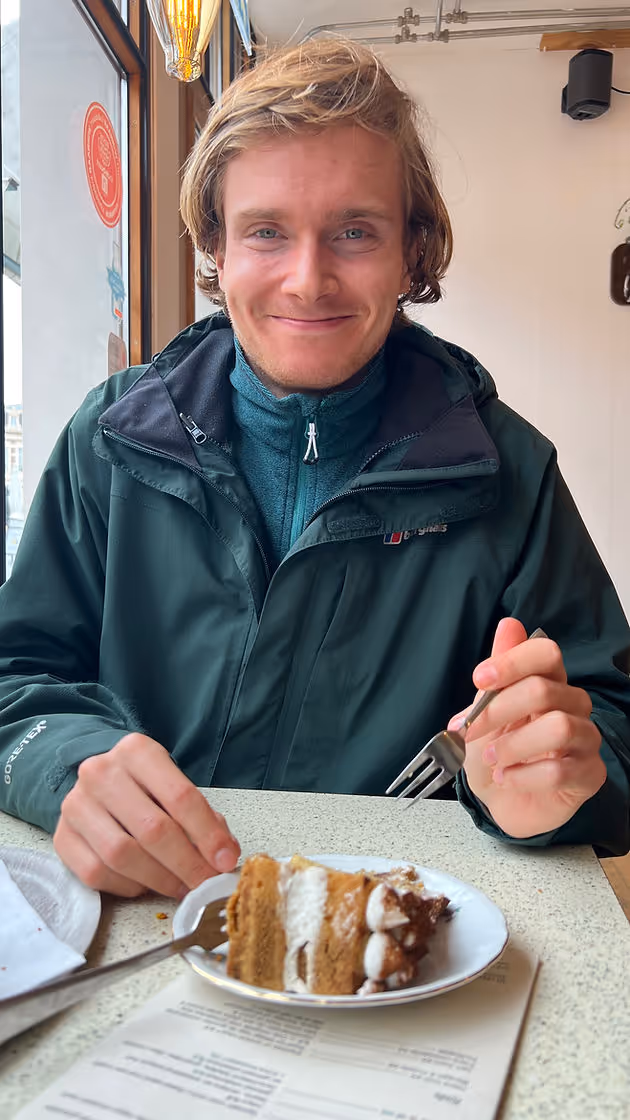 man smiling about to eat cake in cafe