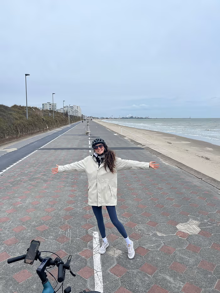 woman standing on Dunkirk promenade with arms outstretched after long cycle
