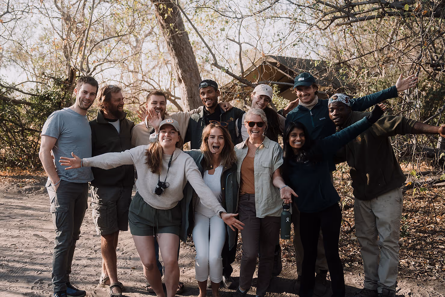 A group of eleven individuals with arms outstretched smiling at the camera