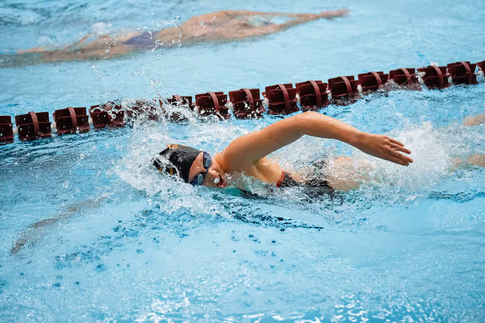 female swimmer in swim cap and goggles swimming in pool
