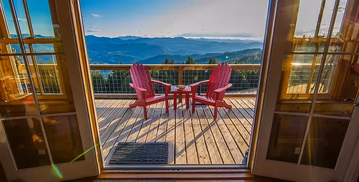 two pink deck chairs on top of high balcony overlooking mountains, forests, and lakes