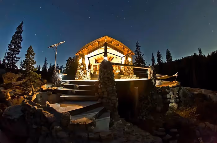 illuminated wooden home made of wood and stone in the middle of forest