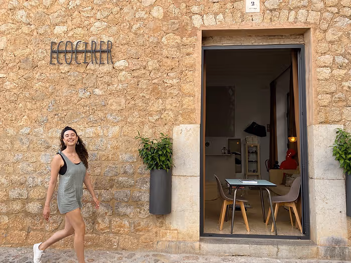 woman walking in front of stone wall front of hotel