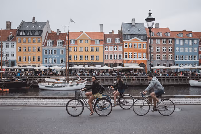 cyclists cycling in front of colourful buildings in Copenhagen