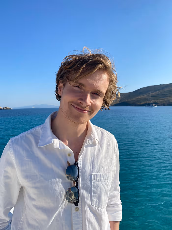man in white linen shirt smiling in front of aqua blue sea