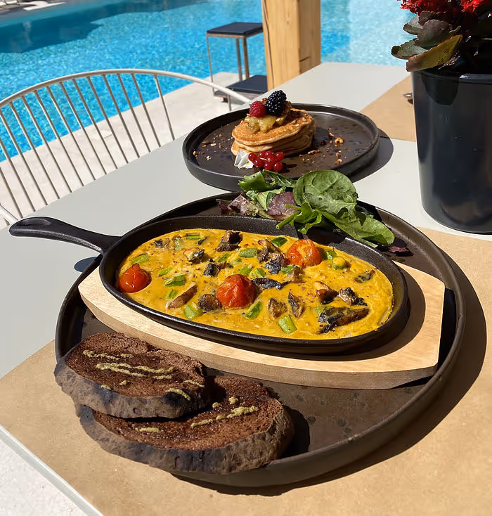 vegan omelette made from chickpeas with bread and vegetables on plate next to swimming pool