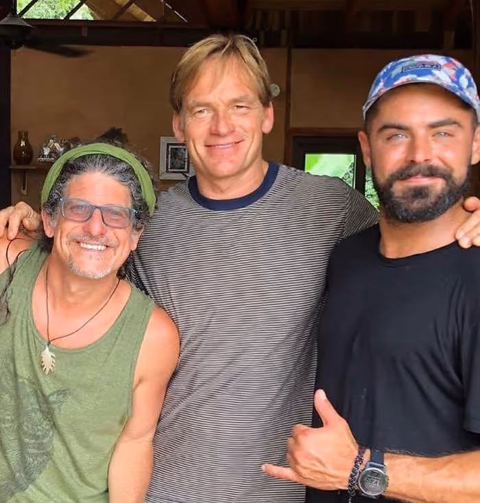 Three men smile at the camera.