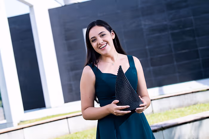 woman standing with award in front of wall