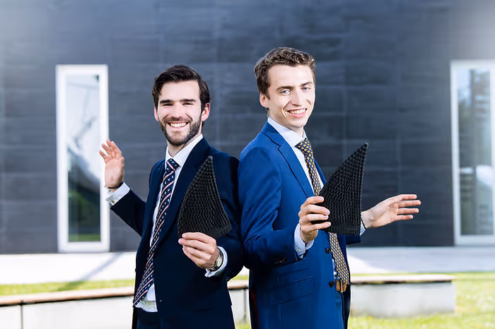 two men standing back to back with suits on