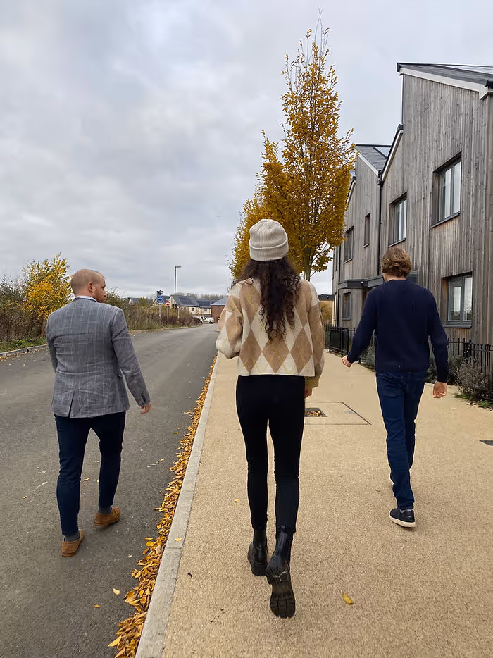 three people walking down sidewalk along houses