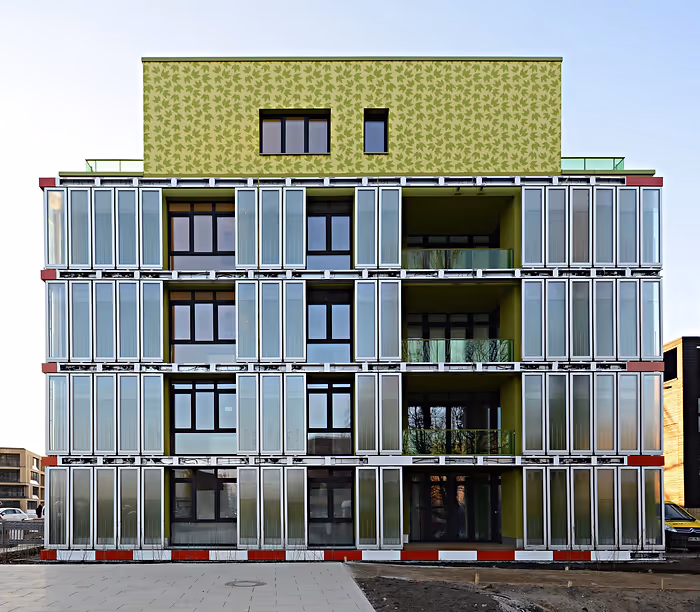 tall modern building covered in solar panels and algae