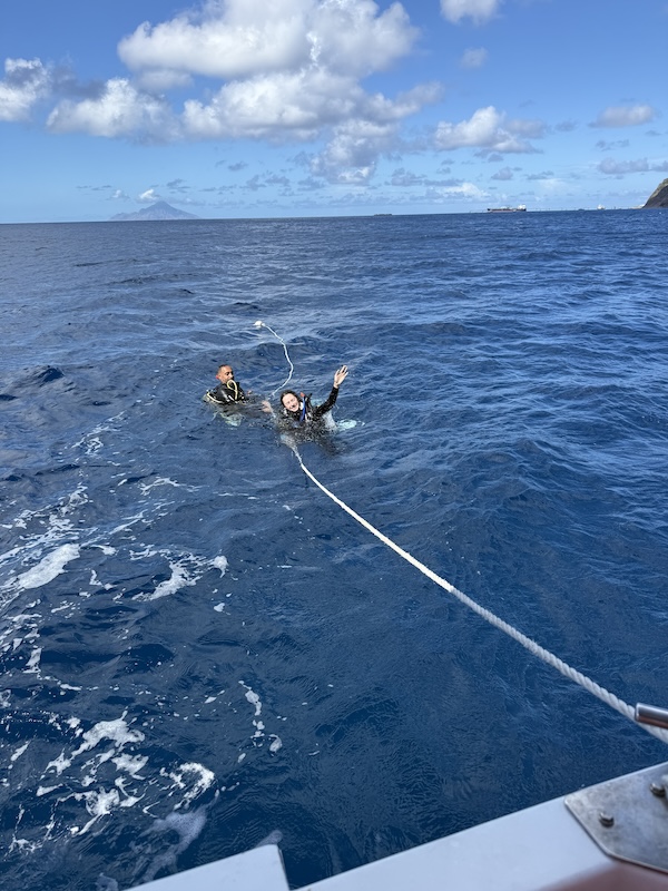 two people swimming in open water holding onto a rope with an island in the background