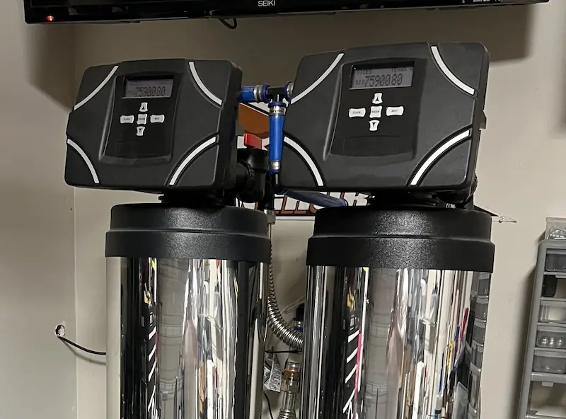 Person repairing or installing a water heater valve using a wrench on tiled floor.