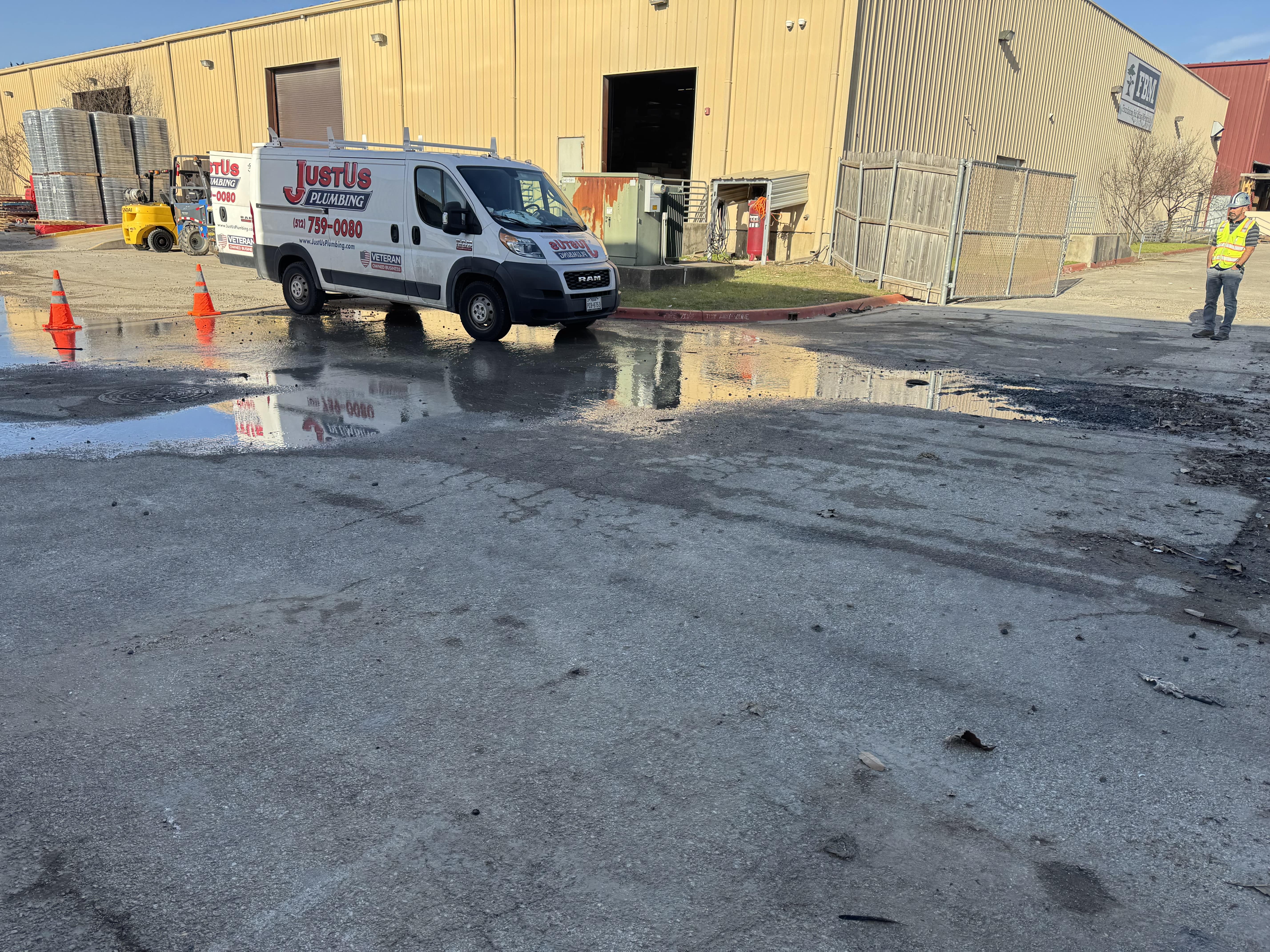 Worker installing white PVC pipes in a dirt trench.