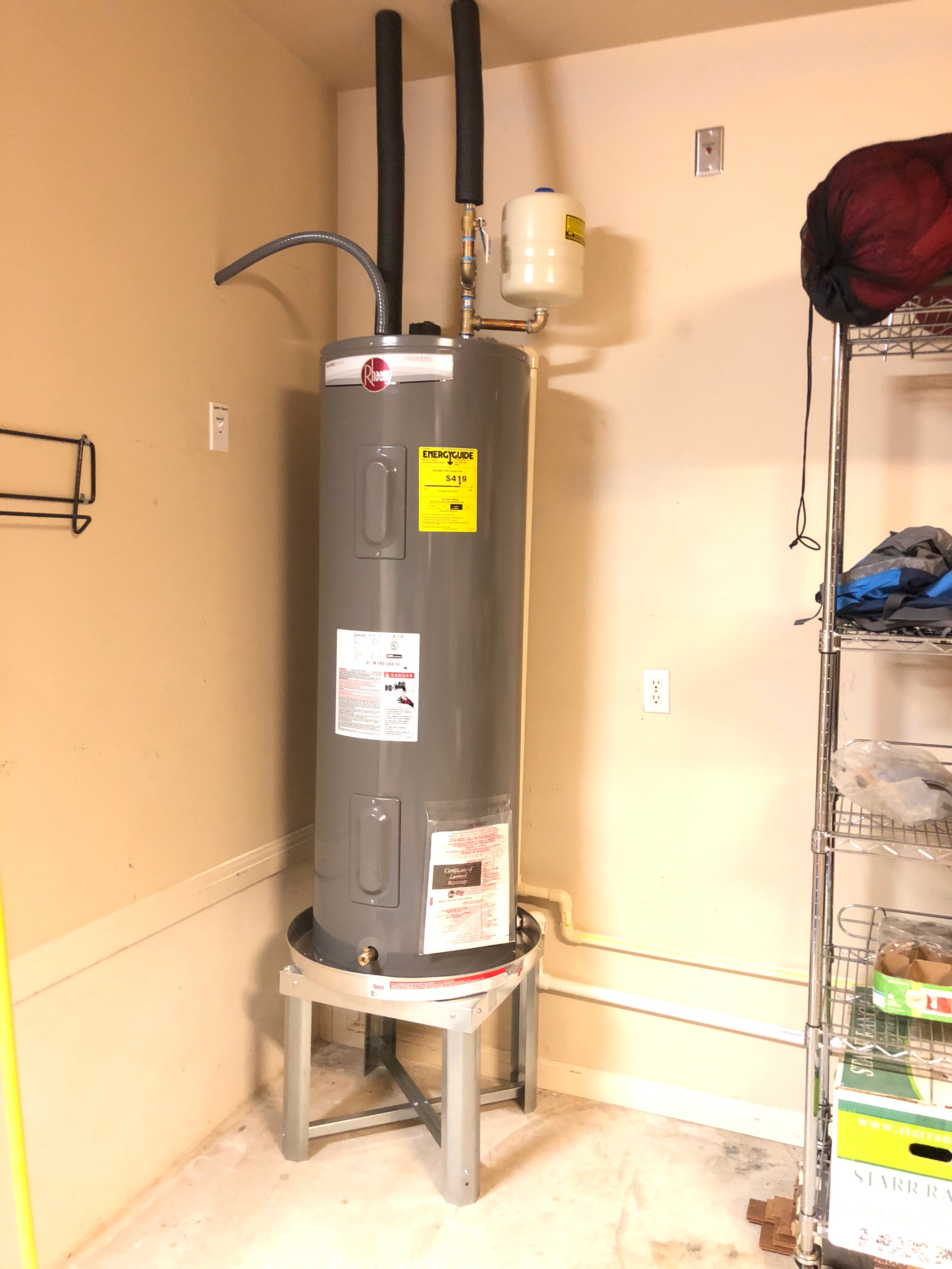 Worker installing white PVC pipes in a dirt trench.
