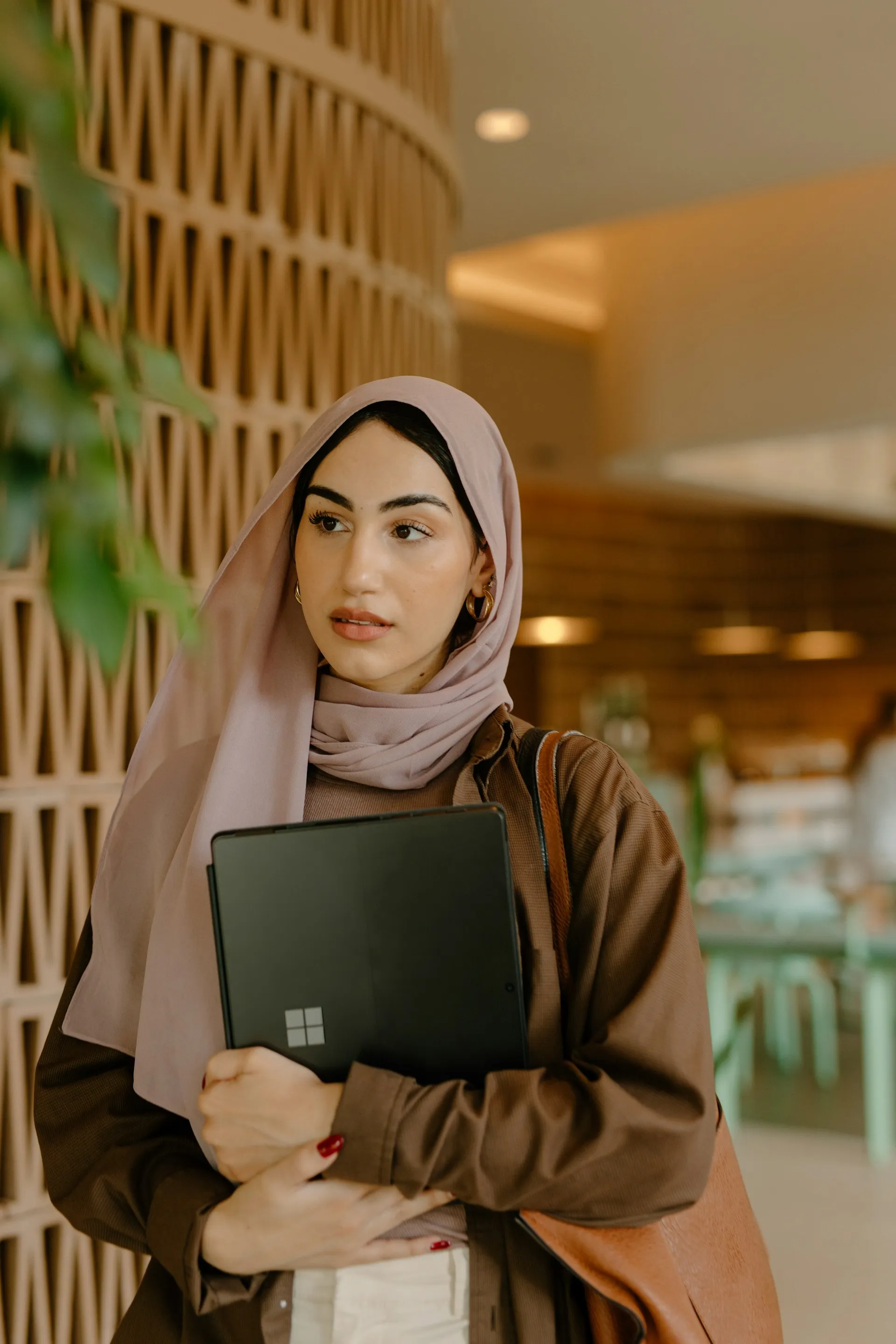 A woman in a hijab holding a laptop computer.