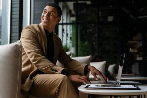A man sitting on a couch using a laptop computer.