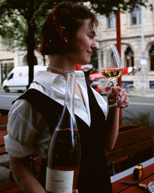Eine Mitarbeiterin von Luzii trinkt einen Wein im Außenbereich vor dem Restaurant