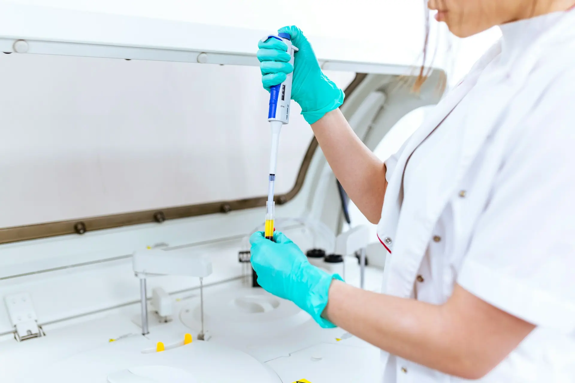 Personnel d'un industriel de la santé en blouse blanche utilisant une pipette dans un laboratoire médical moderne pour analyser des échantillons.