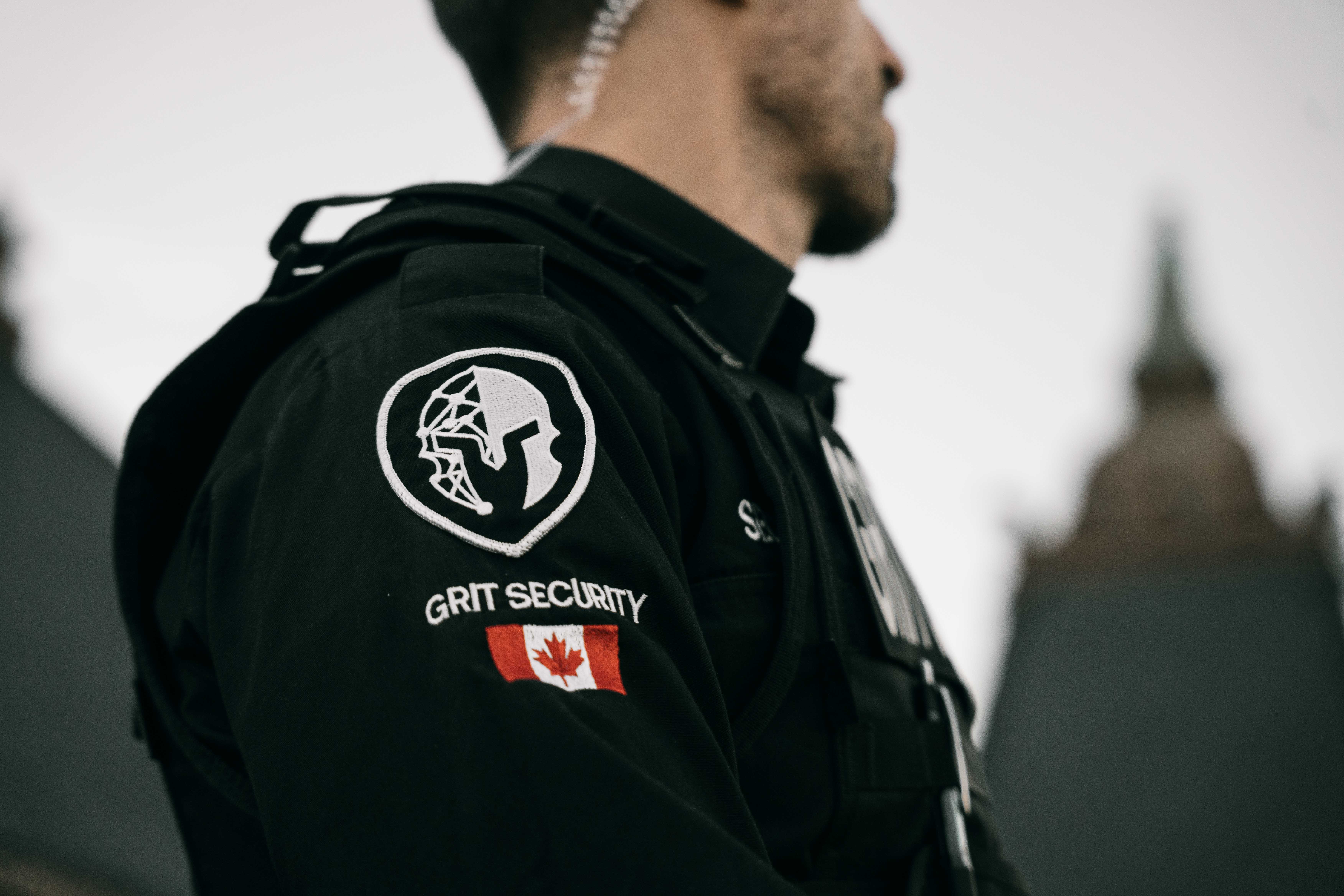 Security guard wearing a black uniform with a Grit Security patch and Canadian flag on the sleeve.