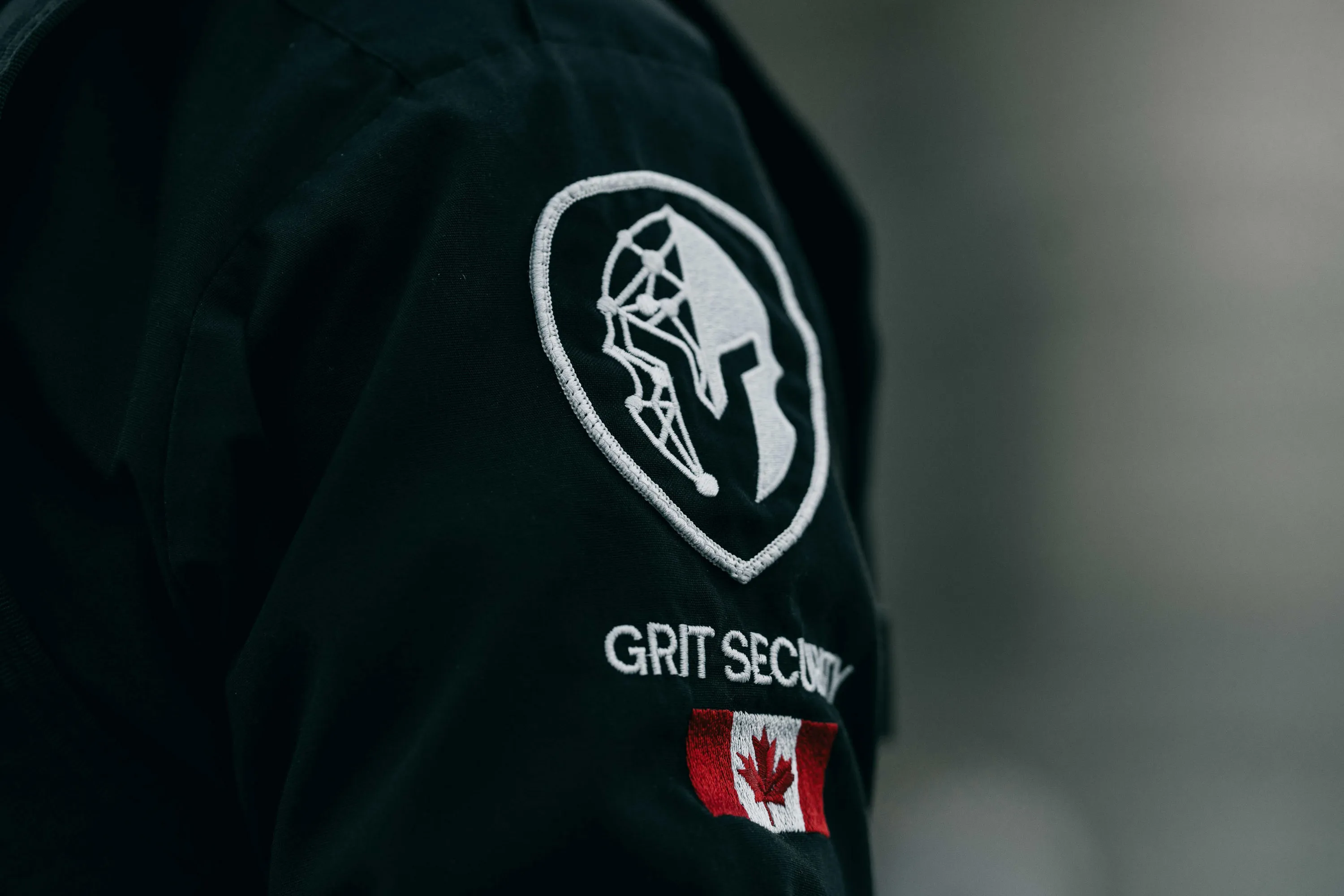 A man wearing a black jacket with a canadian flag on it.