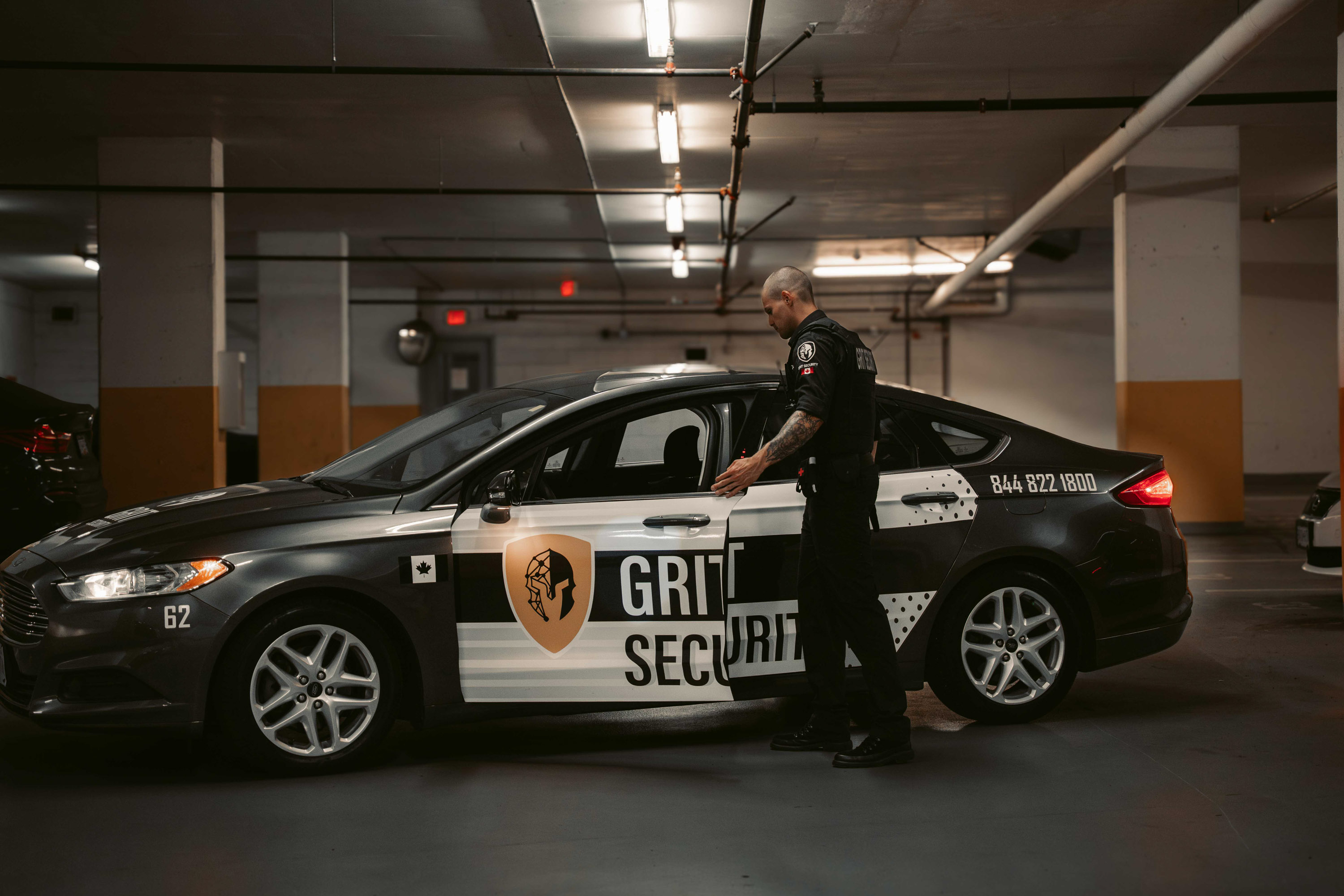 Grit Security mobile patrol officer opening a branded patrol vehicle in an underground parkade