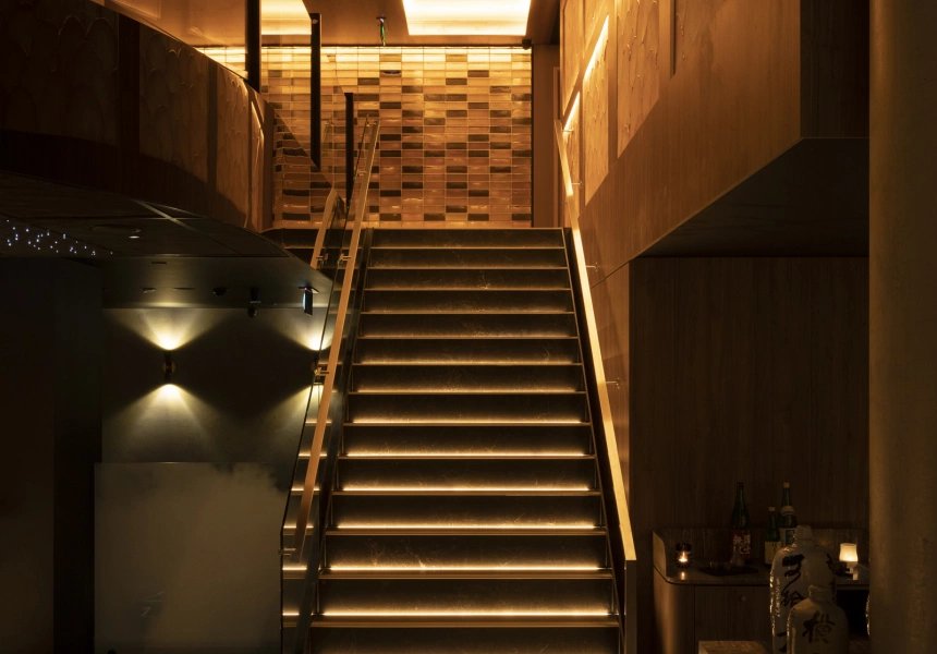 Illuminated indoor staircase with warm yellow lighting and wooden accents in a modern interior.