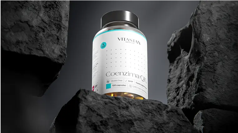 Bottle of Vitastian Coenzima Q10 dietary supplement capsules placed among dark gray rocks.