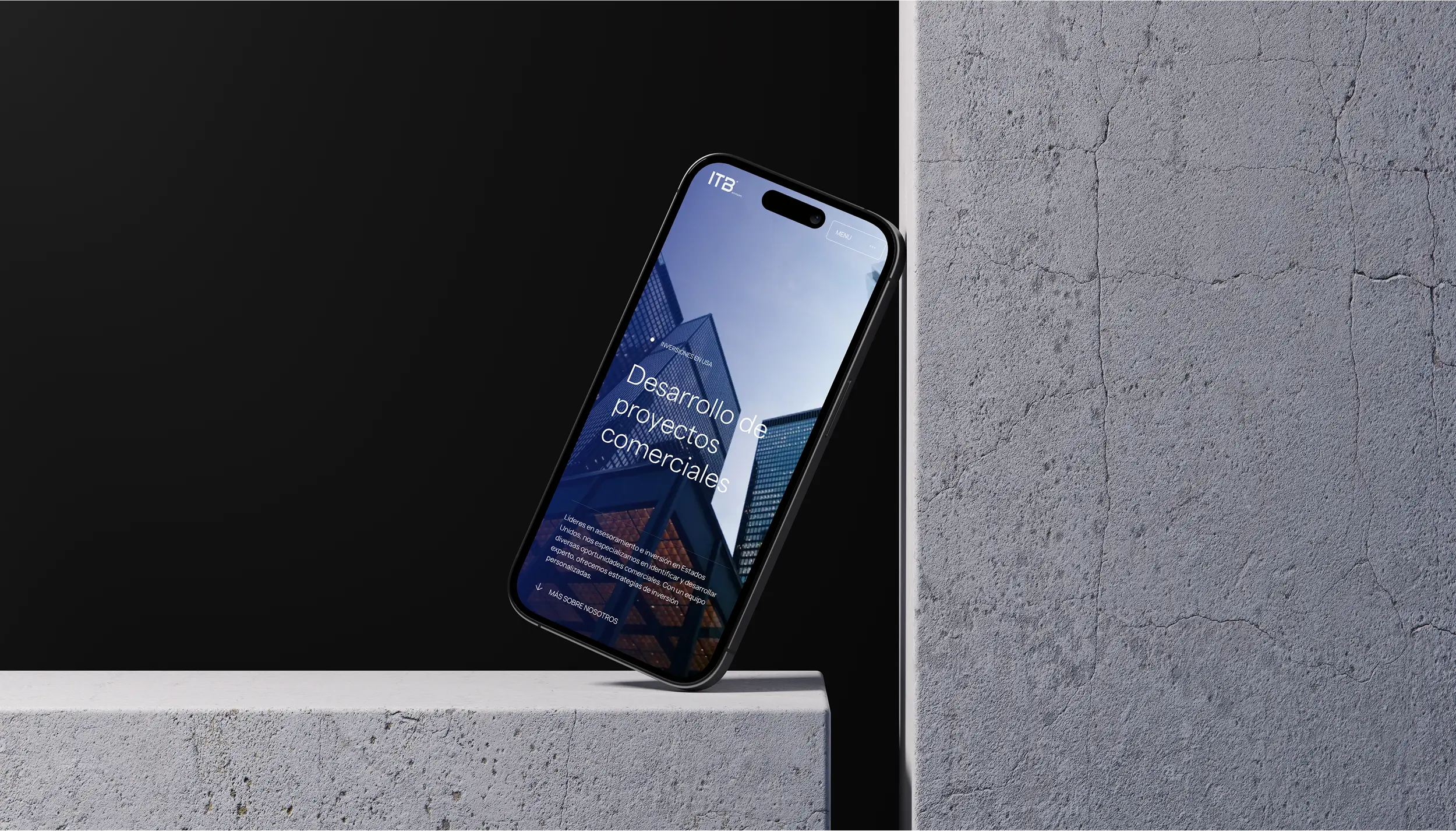 Smartphone displaying a commercial project development website, balanced on the edge of a concrete surface against a dark background.