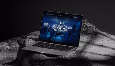 Laptop displaying a digital dashboard interface with a global map on a rocky surface background.