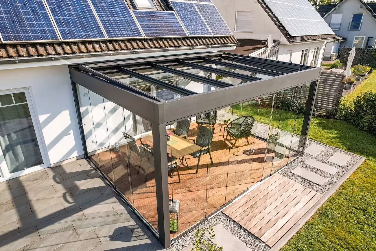 An aluminium pergola with glass sides in a garden.