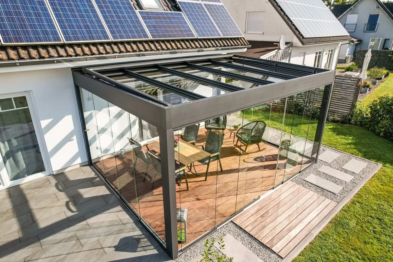 An aluminium pergola with glass sides in a garden. 
