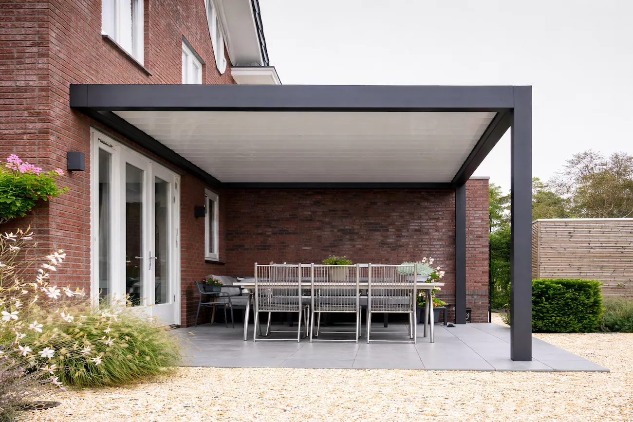Bespoke aluminium pergola with dark grey frame over a wall-mounted patio dining area.