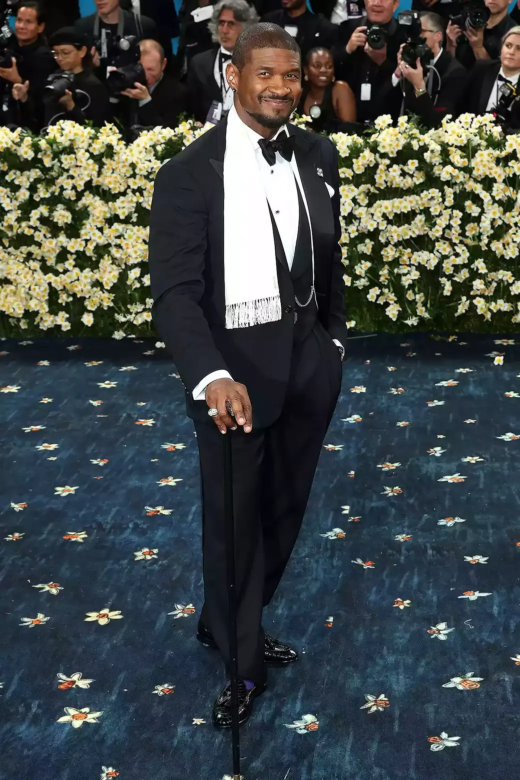 Usher wore a classic black three-piece suit that he paired with a bowtie, a silver button closure chain, a glittering brooch as well as a white scarf, leaning toward progressive dandyism rather than retro references Usher wore a classic black three-piece suit that he paired with a bowtie, a silver button closure chain, a glittering brooch as well as a white scarf, leaning toward progressive dandyism rather than retro references