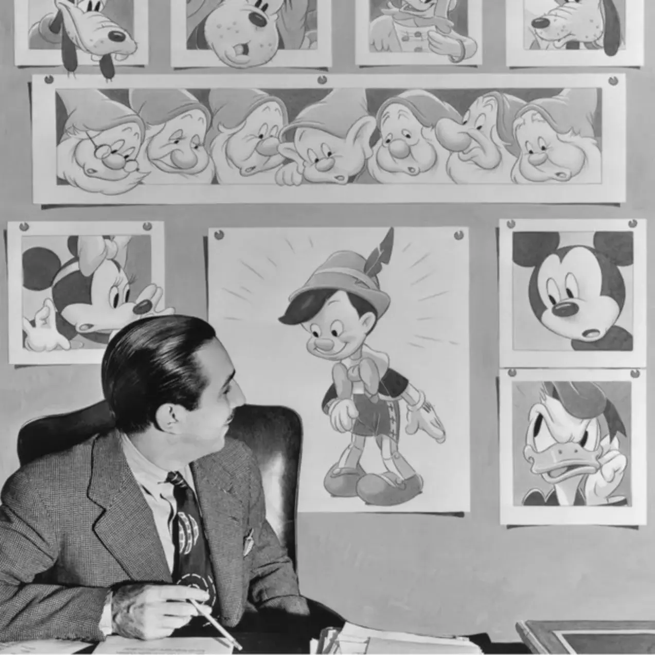 Walt Disney looks up at one of his newest creations, Pinocchio, while some of his other beloved creations also look on (1939)