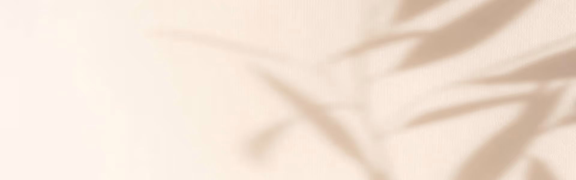 Soft shadow of leaves on a cream-colored fabric background.
