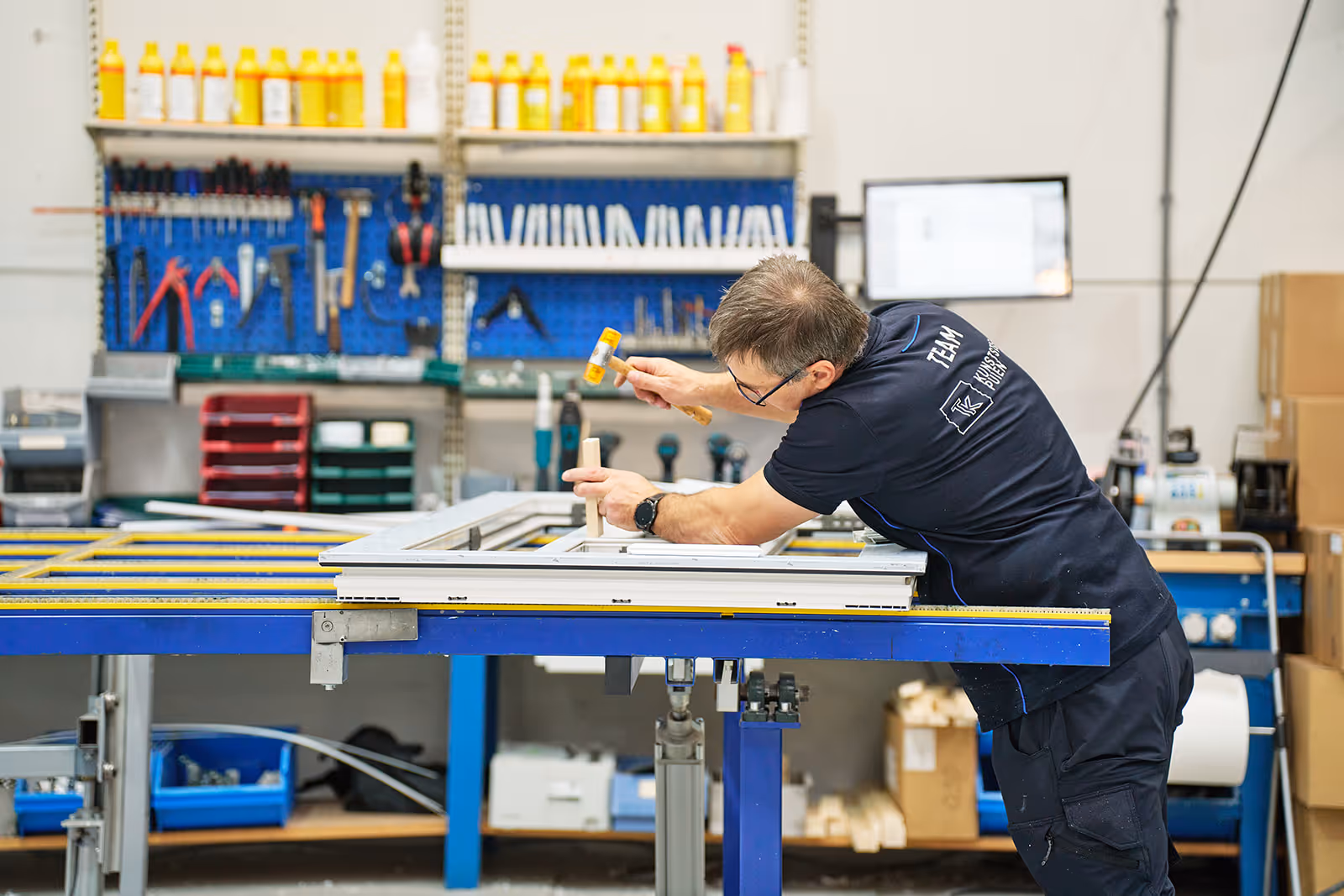 Foto van een man die bezig is met de montage/productie van een deur of kozijn.