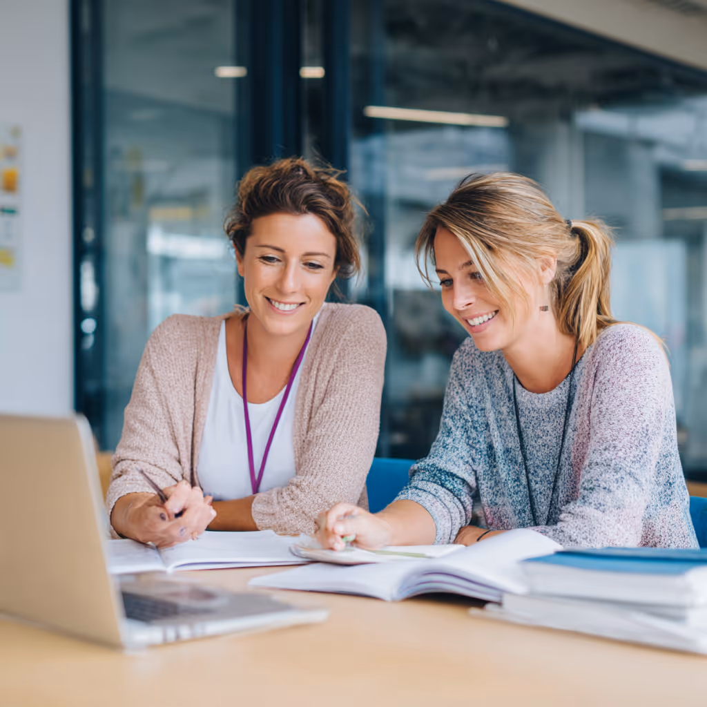 Man wearing striped shirt and pants with sunglasses reading a book while leaning against a stone wall in warm sunlight.